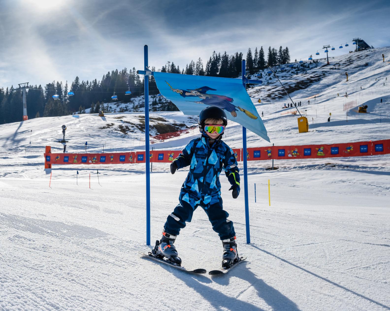 Kleiner Junge in Skikleidung auf Skiern beim Zwergerl-Skikurs im Skigebiet Sudelfeld