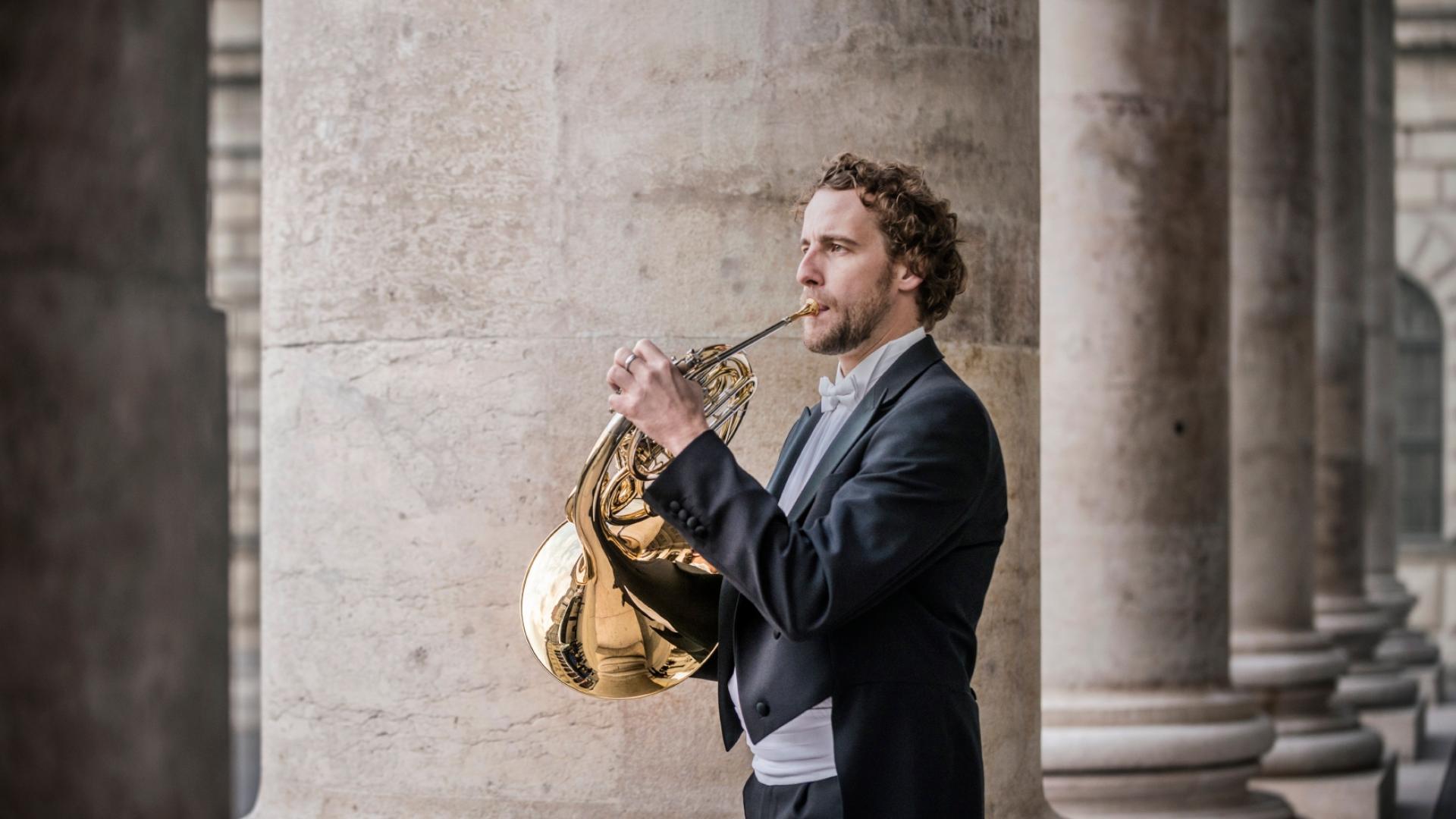 Christian Loferer spielt auf dem Horn vor der Bayerischen Staatsoper in München